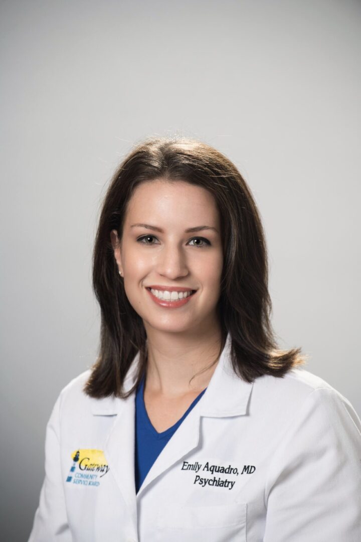 Smiling female doctor in white coat with gray background.